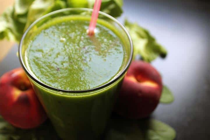 Photo of green smoothie in glass with pink straw and peaches from "Easiest Starter Green Smoothie" recipe by Green Smoothie Girl