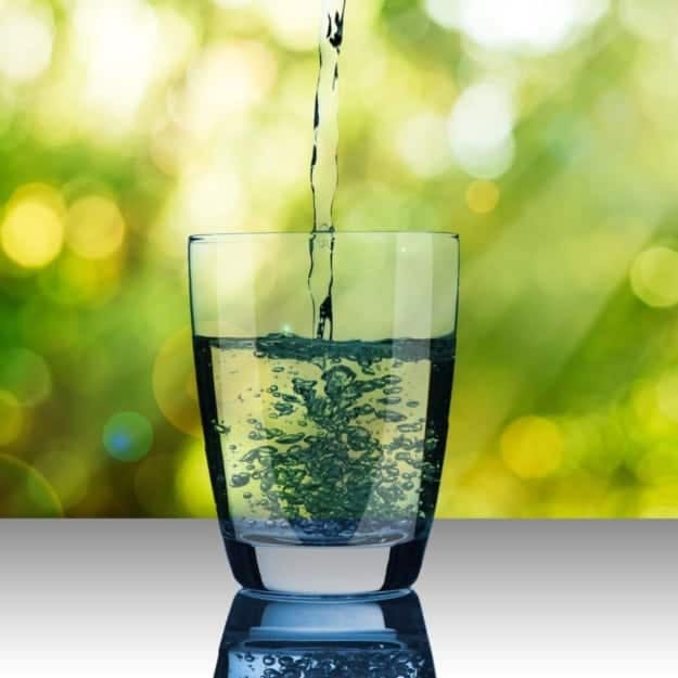 Fluoride is now present in in tap water across the United States. Photograph of a glass being filled with tap water.