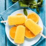 Photo of orange popsicles on top of orange slices and white place from "Orange Dreamsicle Popsicle" recipe by Green Smoothie Girl