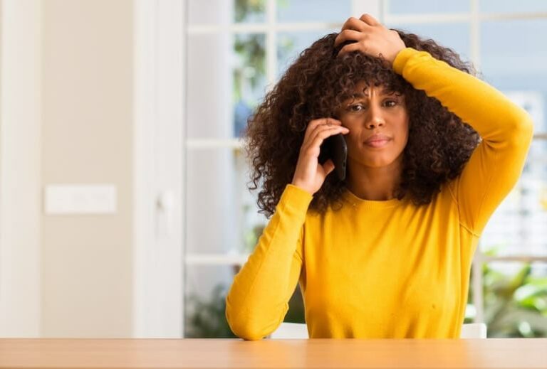 Photo of distraught African American woman holding cell phone to her ear from "Is EMF Making You Sick?" blog post from Green Smoothie Girl