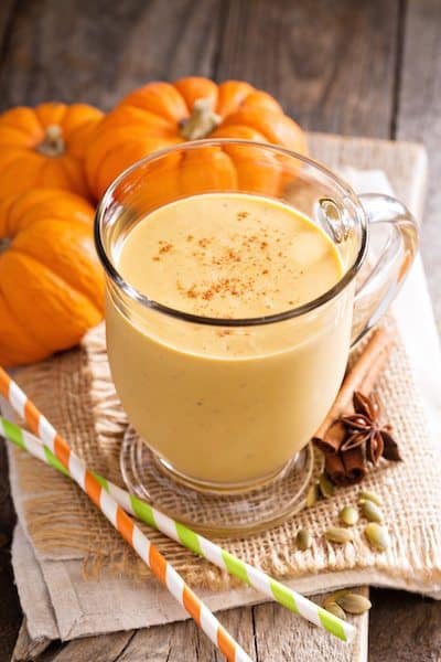 Photo of pumpkin pie smoothie in glass with cinnamon and mini pumpkins surrounding from "Pumpkin Pie Smoothie" recipe by GreenSmoothieGirl