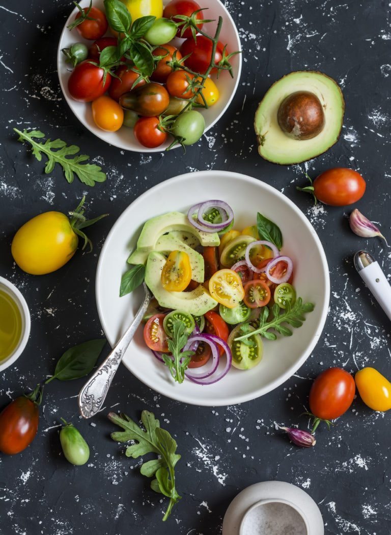 Photo of tomatoes, avocados, greens in bowl from "Avocado Almond Salad" recipe by Green Smoothie Girl