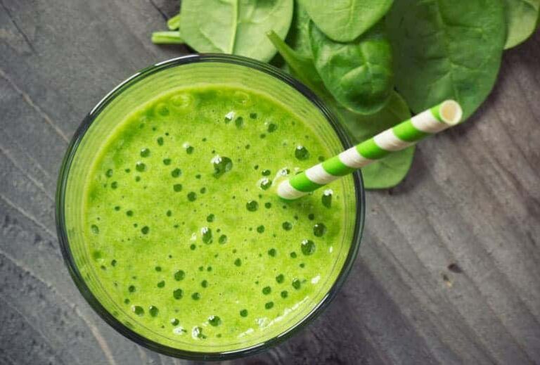 Photo of topdown view of green smoothie with green striped paper straw in it and spinach surrounding from "{VIDEO} Why Are You Afraid of Detoxing?" by Green Smoothie Girl