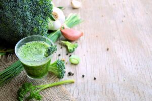 photo of green smoothie with broccoli, garlic, and green onions surrounding from "{VIDEO} Could Toxicity Be Why I'm Sick? (7 Types of Toxins In Your Body)" by Green Smoothie Girl