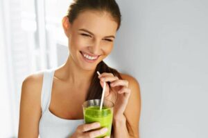 Photo of woman smiling while holding a green smoothie and straw up to lips from "{VIDEO} Why Are You Afraid of Detoxing?" by Green Smoothie Girl