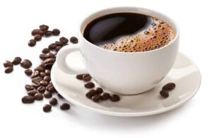 Photo of coffee in white cup with coffee beans on side from "3 Ways To Make Your Coffee Healthier" by Green Smoothie Girl