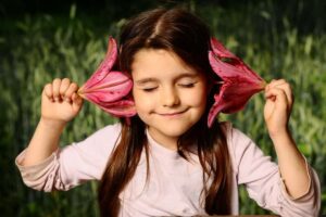 Image of a young girl holding flowers by her ears, from "Which Natural Treatments for ADHD Symptoms Are Backed by Science?"