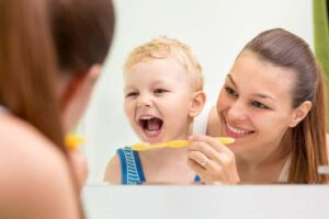  A mother brushing her son's teeth from "Can Soda Dissolve Teeth? The Worst Drinks For Dental Health" by Green Smoothie Girl
