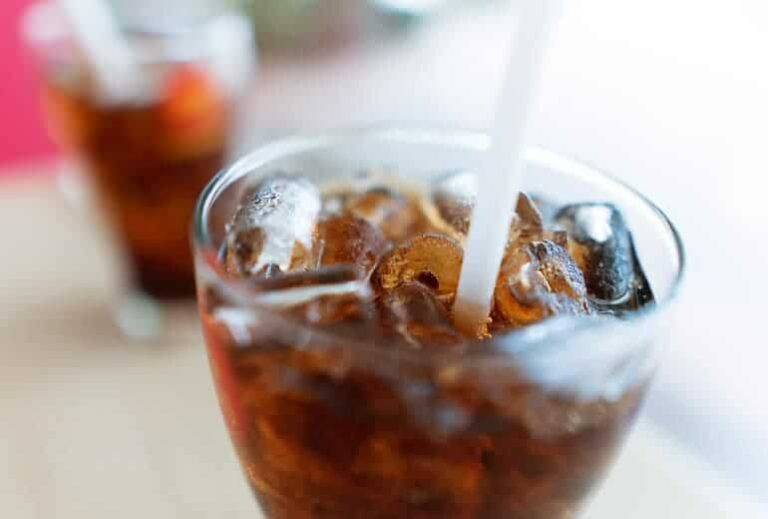 Photo of brown soda with straw and ice from "Can Soda Dissolve Teeth? The Worst Drinks For Dental Health" by Green Smoothie Girl