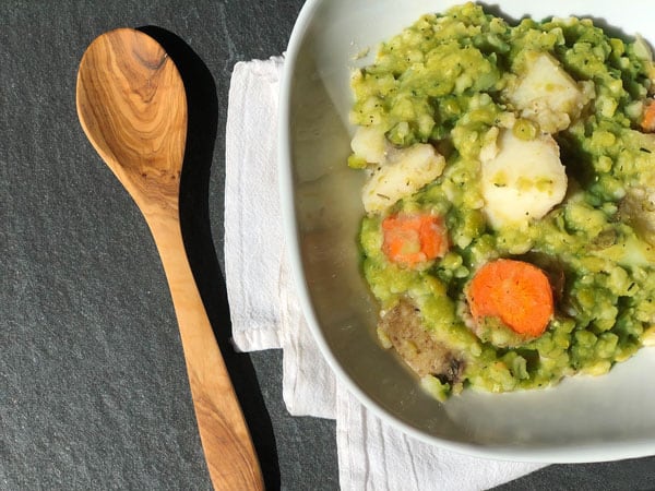 Photo of split pea soup in white bowl and wooden spoon from "My Famous Split Pea Soup" recipe by Green Smoothie Girl