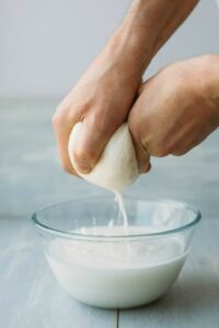Photo of hands squeezing ball of sprouted almonds into milk from "13 Top Raw Almonds Nutrition Benefits (And How To Get Truly Raw Almonds)" by Green Smoothie Girl