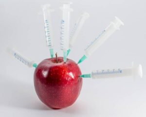 Photo of apple with syringes, from "What Does “Organic” Really Mean" at Green Smoothie Girl.