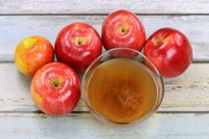 Photo of fresh apples and bowl of raw unfiltered organic apple cider vinegar from"Mums’ Magical Antiviral Hot LemonAid Tonic" by Green Smoothie Girl