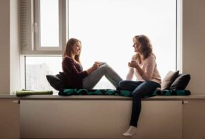 Photograph of a mother and teenage daughter talking in front of a window, from "9 Ways to Get Kids to Drink Healthy Green Smoothies" at Green Smoothie Girl.