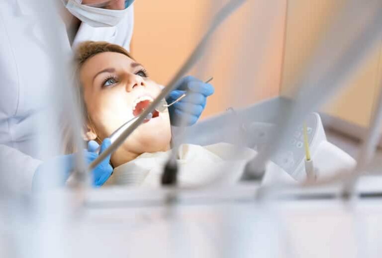 Photo of woman with mouth open and dentist with surgical tools from "What Happened When My Root-Canal Teeth Were Pulled" by Green Smoothie Girl