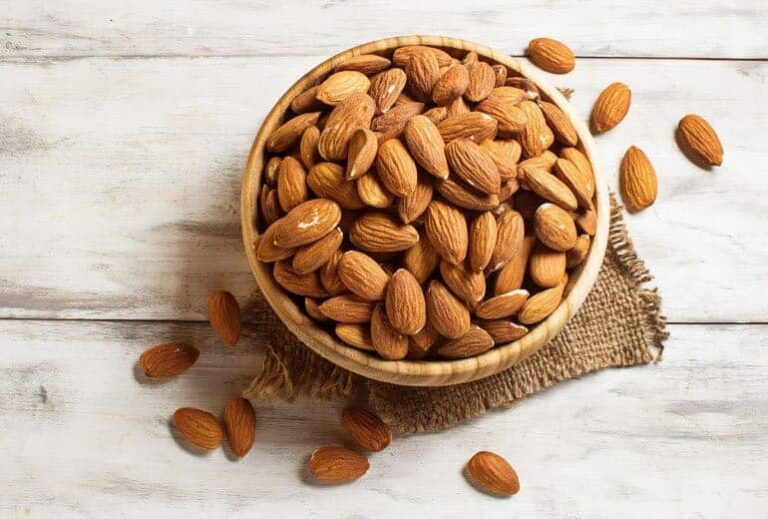 Photo of bowl of almonds on wooden table from "13 Top Raw Almonds Nutrition Benefits (And How To Get Truly Raw Almonds)" by Green Smoothie Girl