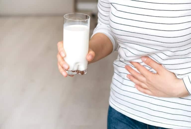 Image of someone holding a glass of milk and grasping at their stomach, from "Top 11 Chia Health Benefits, and How I Use It Every Day" at Green Smoothie Girl