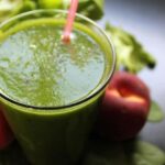 Photo of green smoothie in glass with pink straw and peaches from "Easiest Starter Green Smoothie" recipe by Green Smoothie Girl