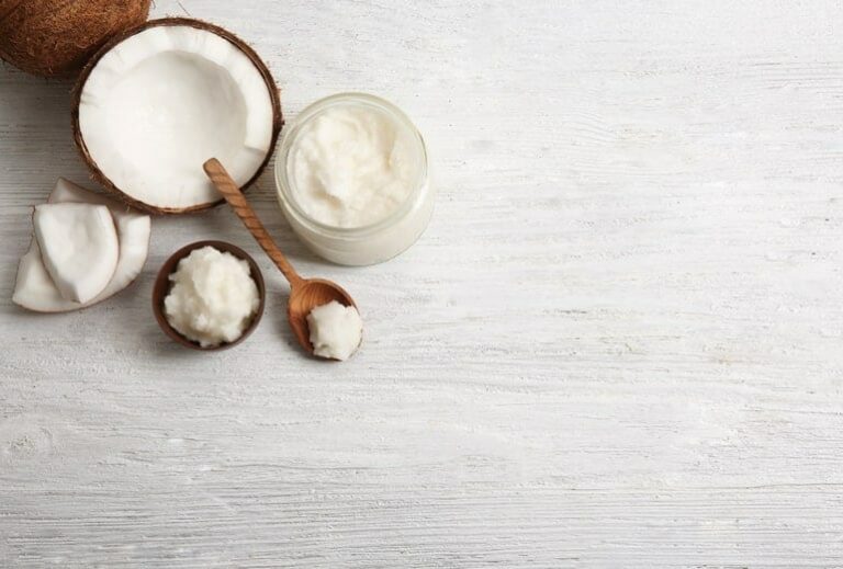 Photo of open coconut with jar of coconut oil from "top 11 benefits of coconut oil and how to use it every day" by Green Smoothie Girl