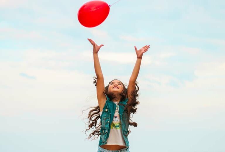 Image of a young girl jumping for a red balloon, from "Which Natural Treatments for ADHD Symptoms Are Backed by Science?"