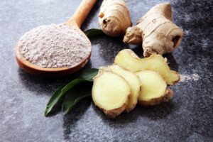 Fresh ginger root and ground ginger spice on dark background, from "Top Proven Ginger Health Benefits and My Favorite Ways to Use It" at Green Smoothie Girl