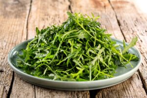Photograph of arugula leaves on a plate, from "Top 11 Greens to Use in Green Smoothies" at Green Smoothie Girl.