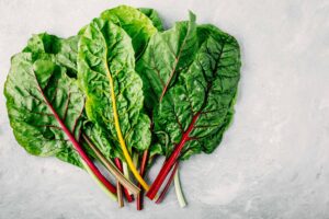 Fresh raw swiss rainbow chard leaves on gray stone background, from "11 Greens to Use in Green Smoothies" at Green Smoothie Girl
