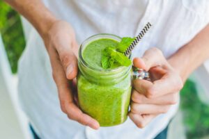 A glass mug filled with green smoothie and a straw, from "How to Freeze Spinach and Other Leafy Greens for Later (With Shortcuts!)" at Green Smoothie Girl.