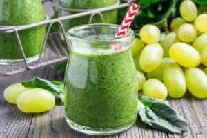 Photograph of a green smoothie in a glass, surrounded by green grapes, from "10 Easy Green Smoothies Kids Will Love" at Green Smoothie Girl