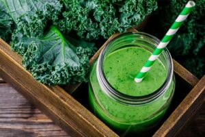 Photograph of a green smoothie surrounded by kale, from "10 Easy Green Smoothies Kids Will Love" at Green Smoothie Girl