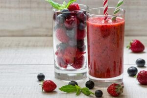 Photograph of a smoothie next to a glass of whole berries, from "10 Easy Green Smoothies Kids Will Love" at Green Smoothie Girl