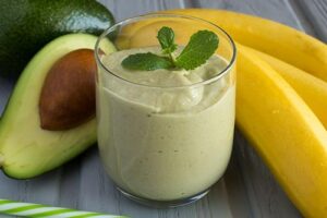 Photograph of a green smoothie in a glass, next to banana and avocado, from "10 Easy Green Smoothies Kids Will Love" at Green Smoothie Girl