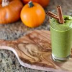 photo of a green smoothie with two cinnamon sticks in it with pumpkins in the background from Green Smoothie Girls's "green pumpkin smoothie"