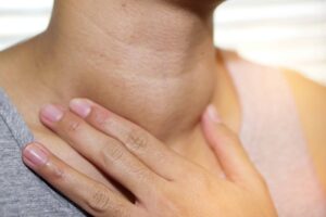 Close-up photograph of a woman touching her neck and feeling her thyroid, from "Health Benefits of Kelp and Dulse (and How to Eat It)" at Green Smoothie Girl.