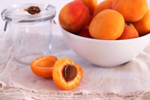 Fresh apricots in a bowl, one apricot just halved, on natural linen cloth and white background, from "Health Benefits of Sulfur, and Why You're Probably Deficient" at Green Smoothie Girl.