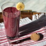 Photo of a pink smoothie topped with a banana slice next to brown sugar from Green Smoothie Girl's "velvety chocolate green smoothie"