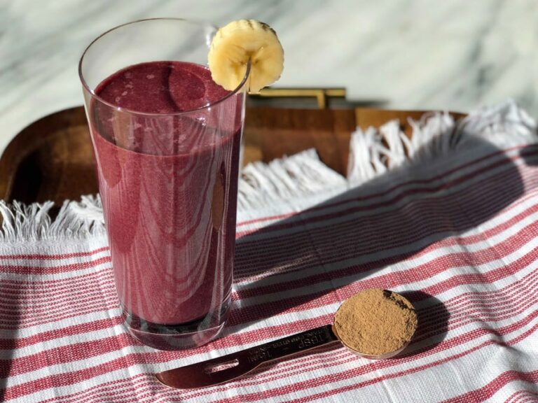 Photo of a pink smoothie topped with a banana slice next to brown sugar from Green Smoothie Girl's "velvety chocolate green smoothie"