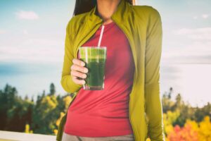 Photograph of a person drinking a green smoothie, from “Why You Should Chew Your Green Smoothies” at Green Smoothie Girl.