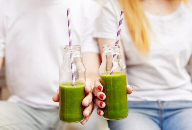 Photo of two people holding a green smoothie, from "Why You Should Chew Your Green Smoothies" at GSG.