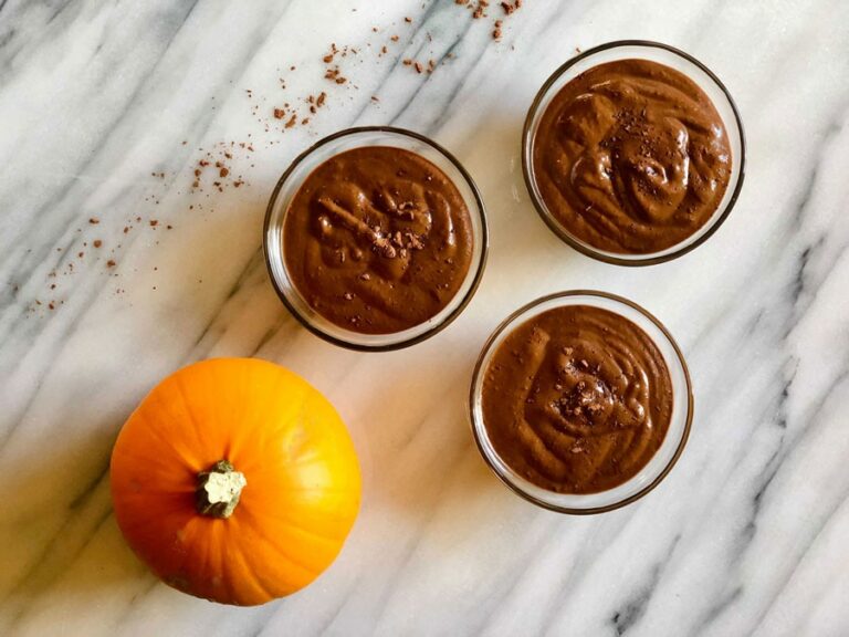 three brown smoothies next to a pumpkin from Green Smoothie Girl's "peanut butter pumpkin pick-me-up smoothie"