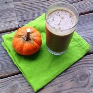 Photograph of a smoothie and a small pumpkin on a green napkin from "Peanut Butter Pumpkin Pick-Me-Up" recipe by Green Smoothie Girl