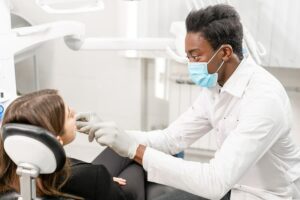 Photo of young African American dentist performing oral checkup on patient from "periodontitis vs gingivitis: know the differences and warning signs" blog post by Green Smoothie Girl