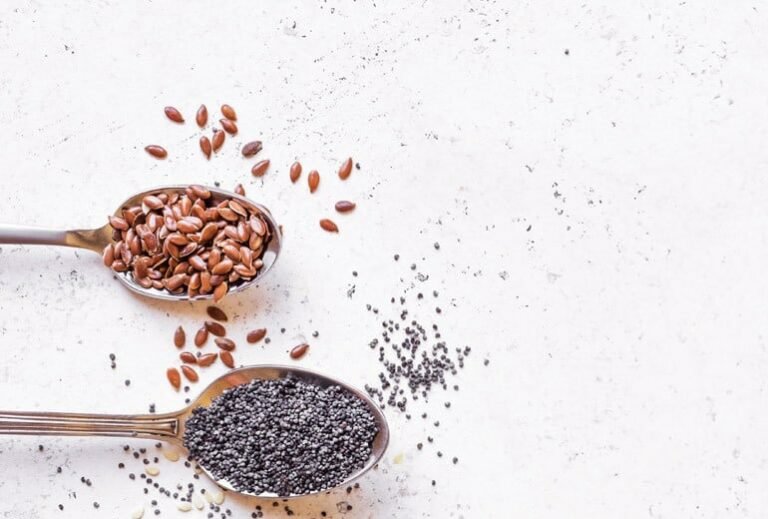 Image of a spoonful of chia seed and a spoonful of flax seed on a white countertop, from "Chia Seed vs. Flax Seed: Similarities, Differences, and When to Use Each" at GreenSmoothieGirl