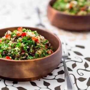 Vegetarian salad with quinoa and veggies in a wooden bowl on a table.