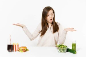 Photo of woman not knowing whether to choose fast food or a salad and green smoothie from "Green Smoothie Recipes for Weight Loss and Fat Burning" by Green Smoothie Girl