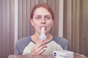 Photo of woman using asthma inhaler from "I Tried Water Fasting Without Food for 40 Days | Here’s What I Learned" at Green Smoothie Girl.
