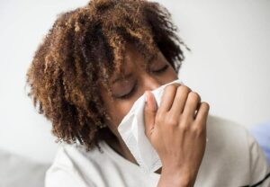 Photo of African American woman sneezing into tissue from "What To Do About Toxic Paint, Carpet, Furniture (Offgassing For Years!)" by Green Smoothie Girl