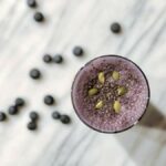 Photo of top-view purple smoothie with blueberries on a marble counter from "Power Green Smoothie" recipe by Green Smoothie Girl