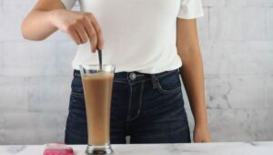 Photo of woman stirring GreenSmoothieGirl chocolate plant protein powder into glass of water from "Modified Fasting 101: The Ultimate Beginner’s Guide" by Green Smoothie Girl