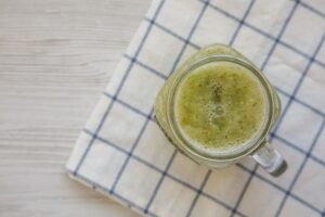 Photo of apple smoothie in a glass jar on a white wooden surface, top view from "Green Apple Smoothie" recipe by Green Smoothie Girl
